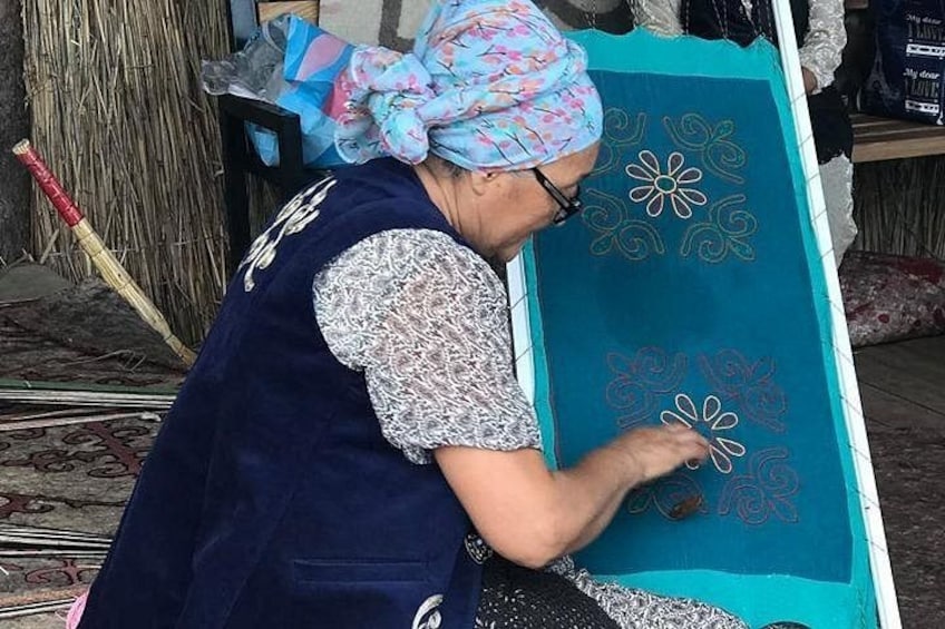 Une personne qui brode un tissu bleu avec des motifs floraux. 3