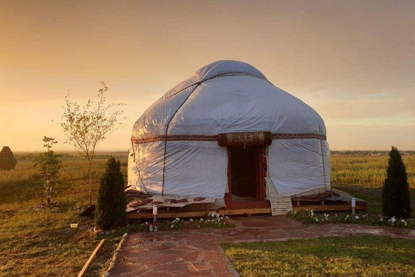Une yourte traditionnelle se dresse dans un champ verdoyant, sous un ciel dégagé. 1
