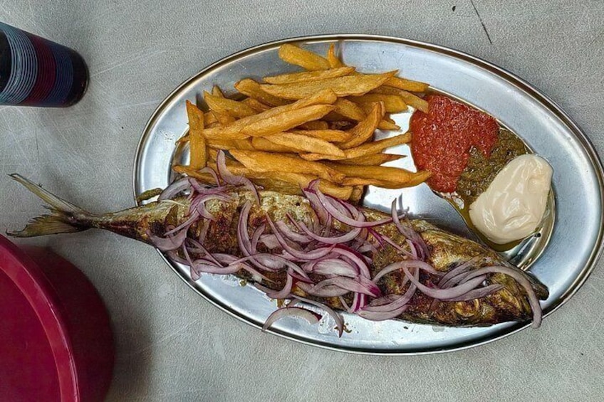 A plate with a whole fish, French fries, red onion slices, ketchup, and mayonnaise. 4