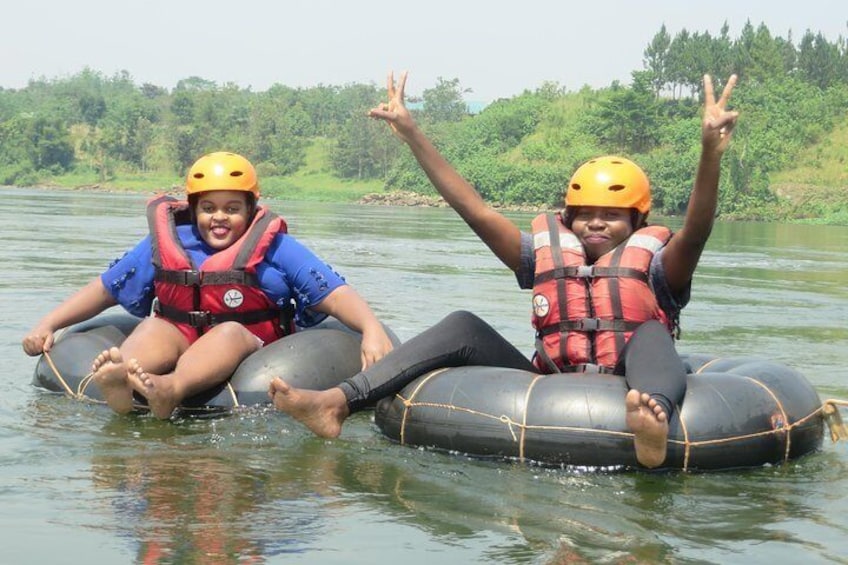 Two people on inflatable rafts in a river, wearing helmets and life jackets. 2