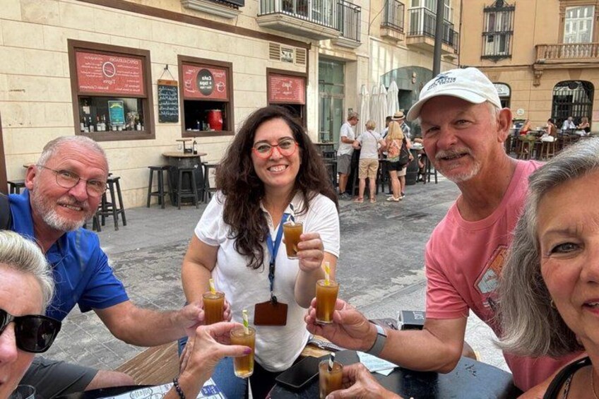 A group of people sitting at an outdoor cafe, holding drinks. 4