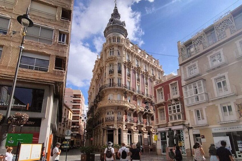 A historic building with ornate architecture, a busy street, and pedestrians. 2