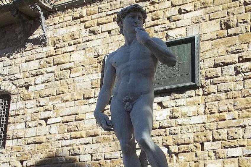 A statue of a male figure with a beard, standing in front of a stone wall with a plaque. 2