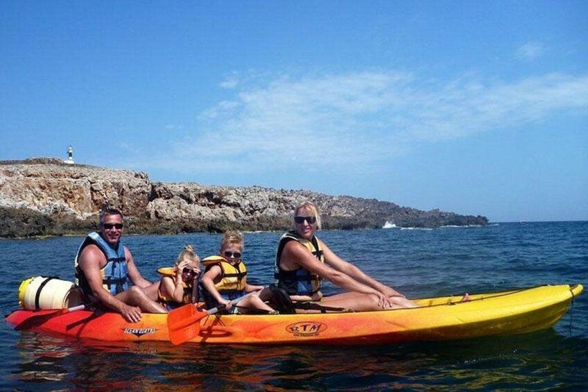 A family kayaking on a calm sea with rocky cliffs in the background. 2