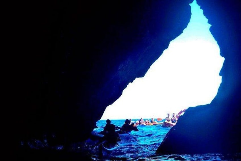 A cave opening with a bright light at the end, water inside, and people at the bottom. 3