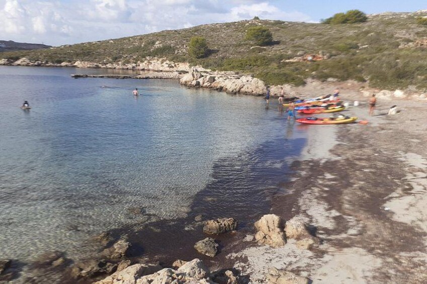 A coastal area with kayaks lined up on the shore, calm water, and rocky terrain. 2