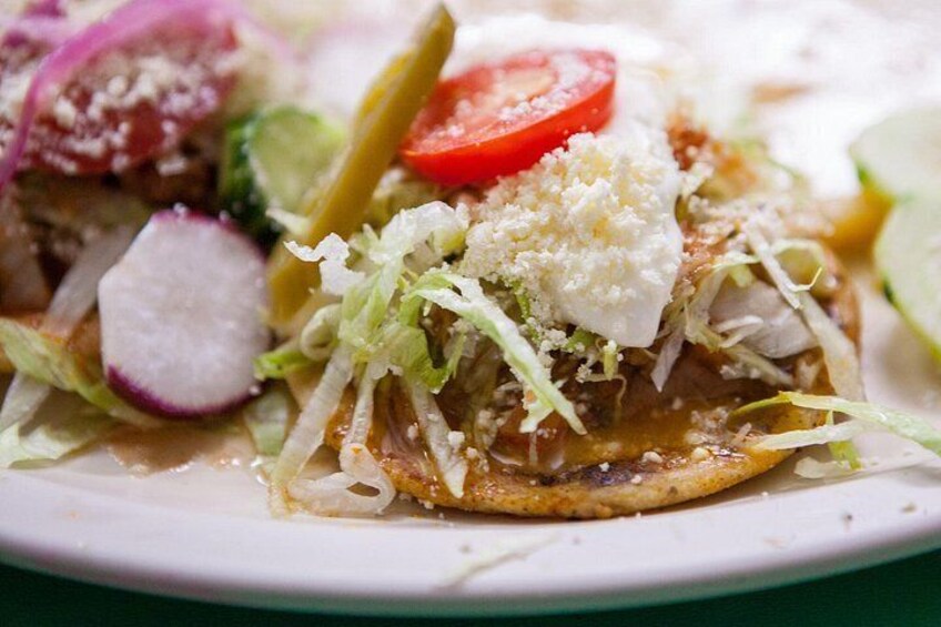Un primo piano di un taco con lattuga, ravanello, pomodoro e formaggio su un piatto. 2