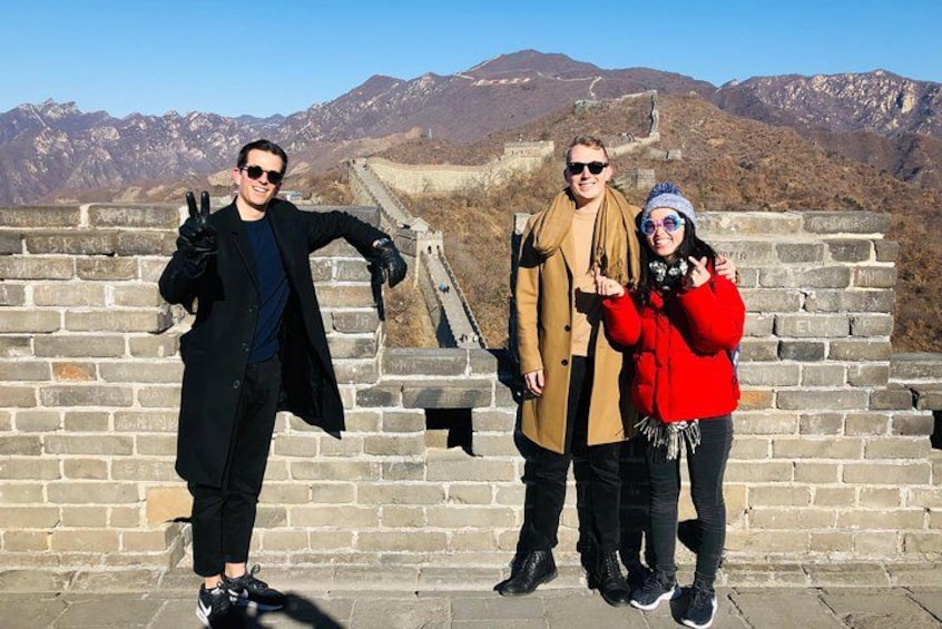 Three people posing on the Great Wall of China with mountains in the background. 3