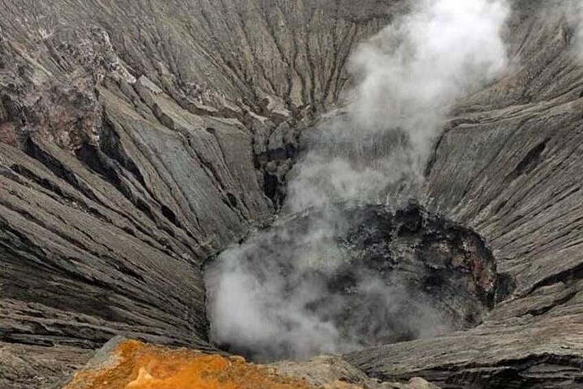 A volcanic crater with steam rising from the center. 1