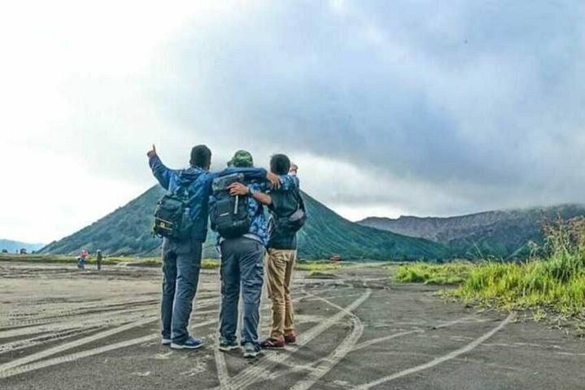 Three people standing on a road with a mountainous landscape in the background. 5