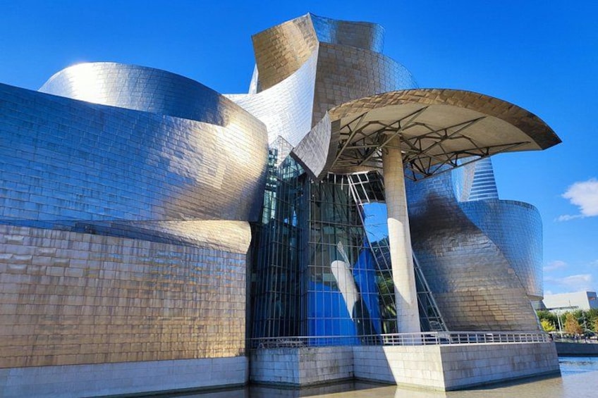 A modern architectural building with reflective metallic surfaces and a distinctive curved design. 1