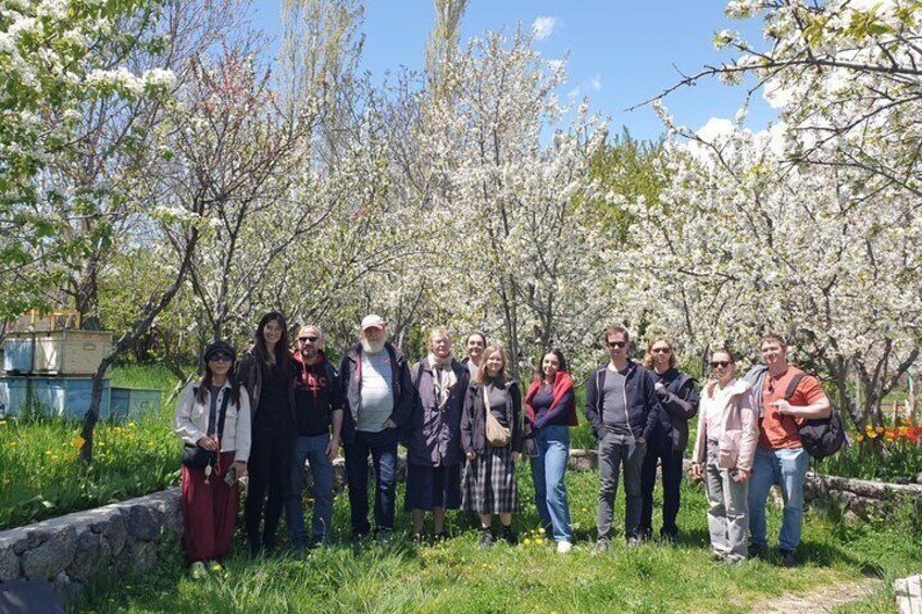 A group of people standing in a garden with blooming trees. 3