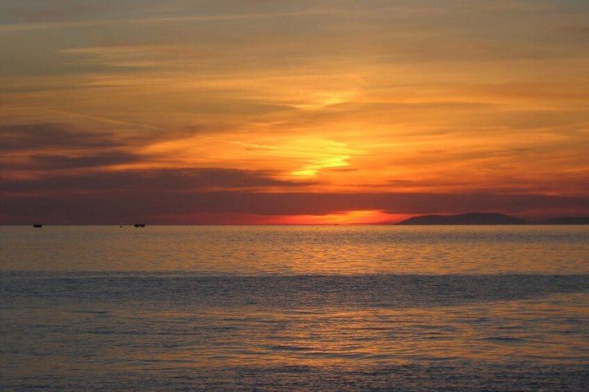 A sunset over a calm sea with a distant landmass. 5
