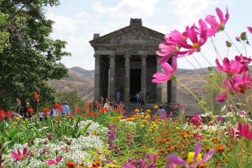 A classical building with columns, surrounded by a colorful garden with various flowers. 4