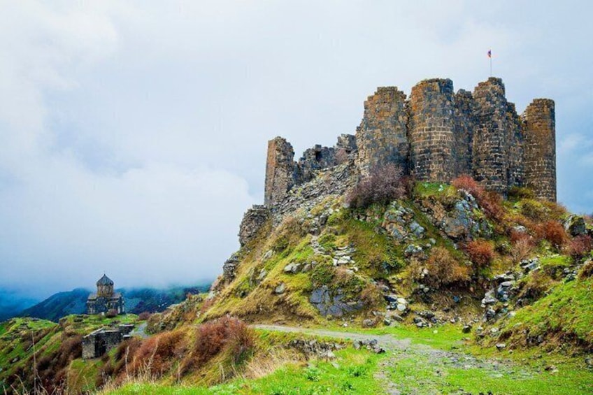 A historic castle on a hill with a small tower in the foreground. 3