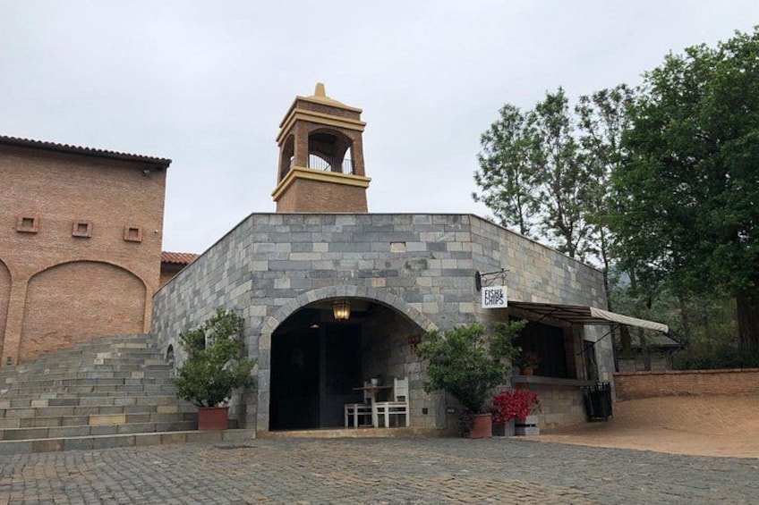 A stone building with a bell tower, an arched entrance, and a sign for 'FISH & CHIPS'. 3