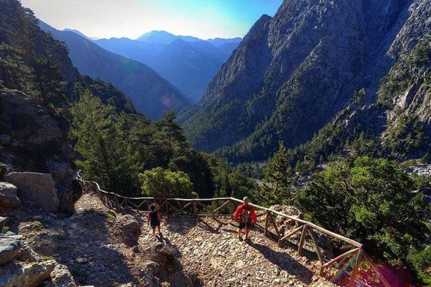 A mountainous landscape with a wooden bridge, rocky terrain, and dense forest. 2