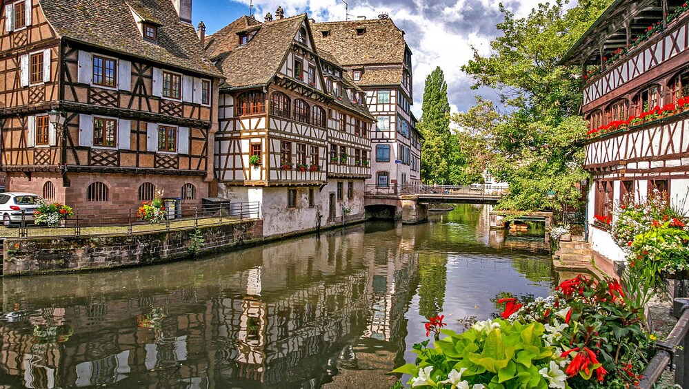 A canal with traditional half-timbered houses, a bridge, and a car parked by the water. 4