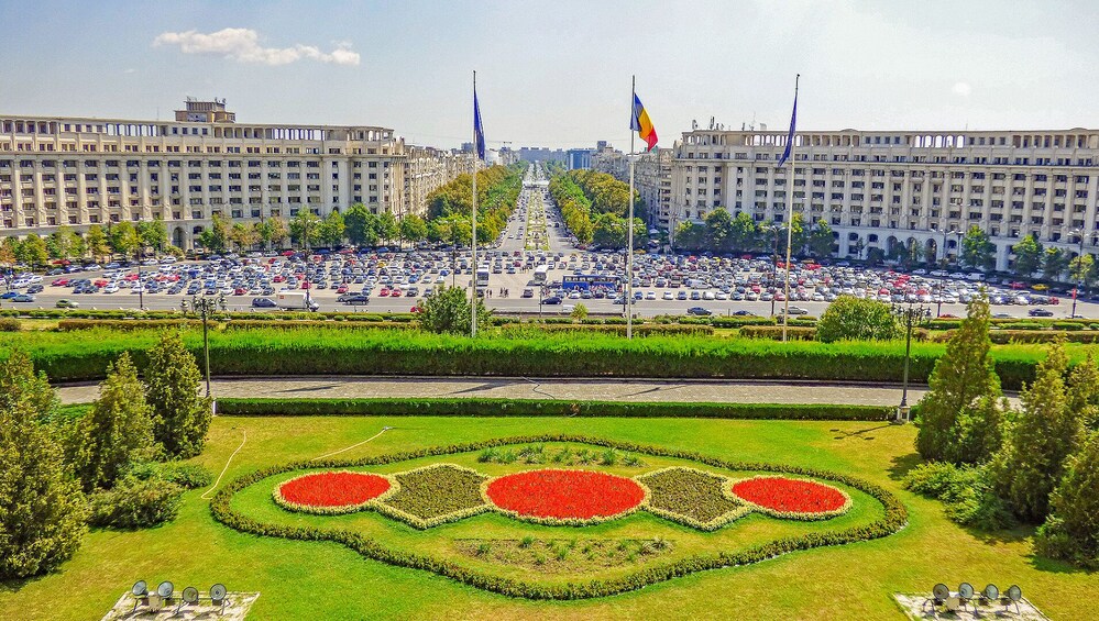 A large urban square with a central monument, surrounded by buildings and a busy road. 5