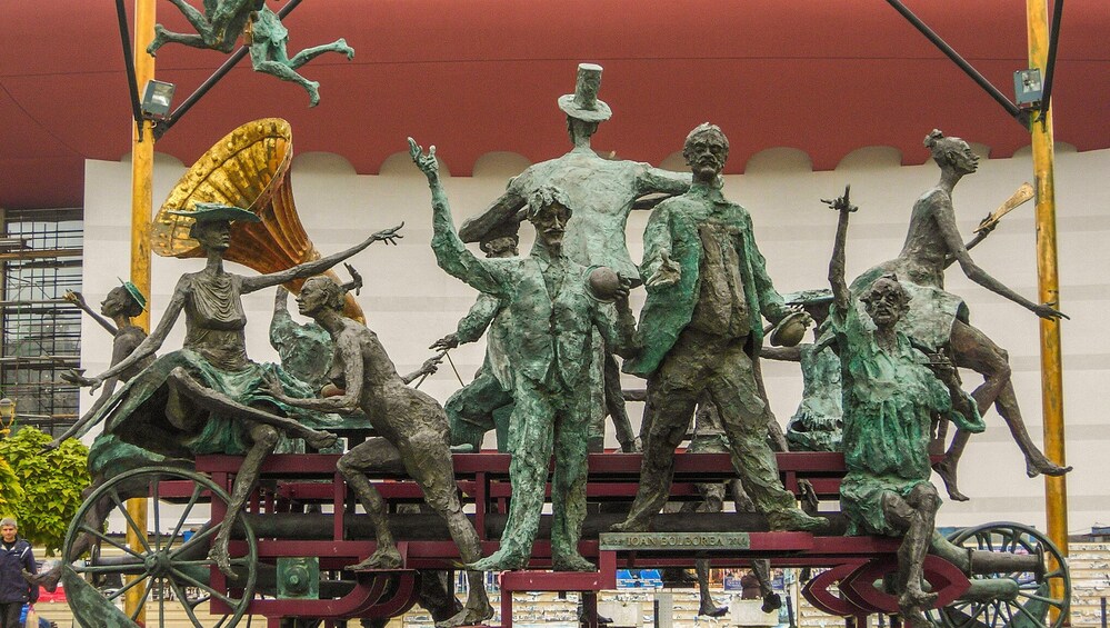 A bronze statue of a man with a hat and a woman with a parasol. 1