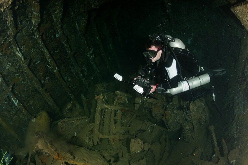 Ein Taucher erkundet eine Unterwasserochse mit Felsformationen, wobei ein Scheinwerfer den Weg erhellt. 4