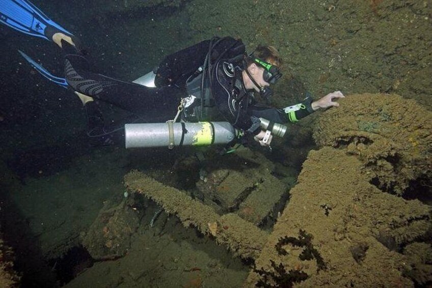 Ein Taucher unter Wasser, in einem schwarzen Neoprenanzug und Flossen, mit Kamera und Tauchmaske. 5