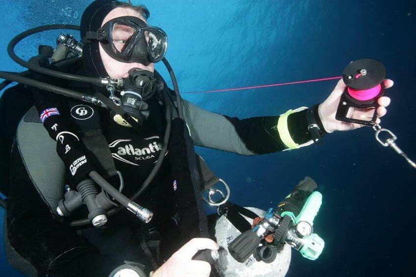 Ein Taucher mit Aquaristik-Ausrüstung hält ein Gerät mit einem pinken Griff. 2
