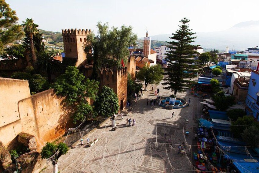 A historic town with a prominent castle, a central square, and surrounding buildings. 3