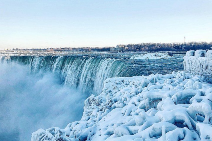 A frozen waterfall with ice formations and a distant city skyline. 5