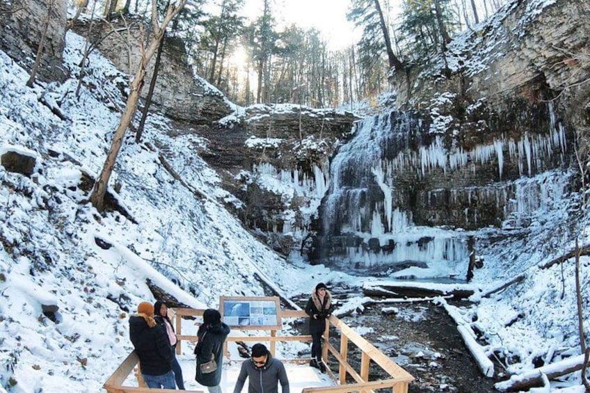 A snowy waterfall with a wooden viewing platform and people observing. 3
