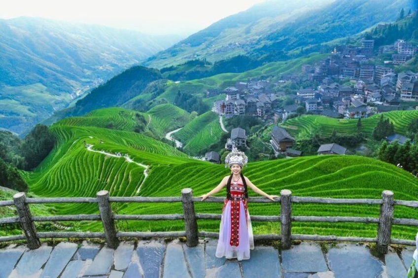 Terraced fields, a person in traditional attire, and a village in the valley. 5