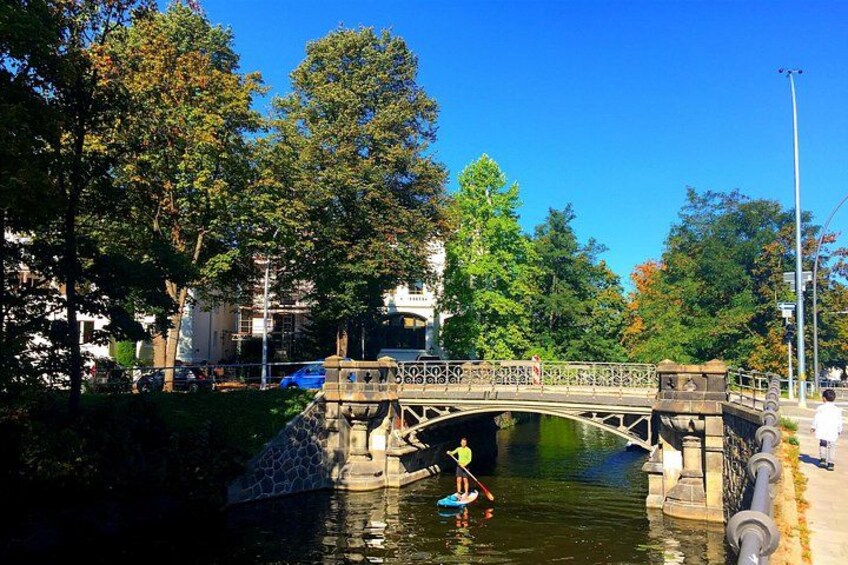 A stone bridge over a canal with a person paddling a kayak. 3