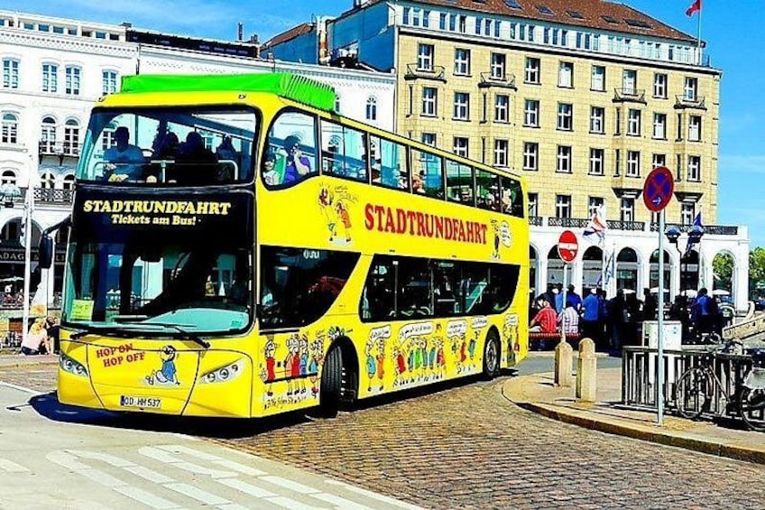 A yellow double-decker bus with 'STADTTRUNDFAHRT' text and 'Tickets am Bus' on the front. 1