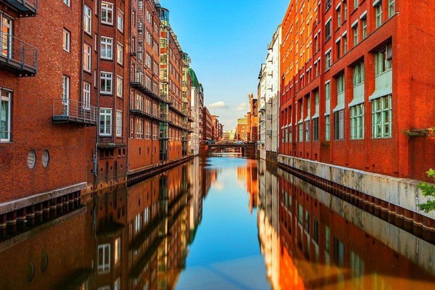 A canal with buildings on either side, reflecting in the water. 2