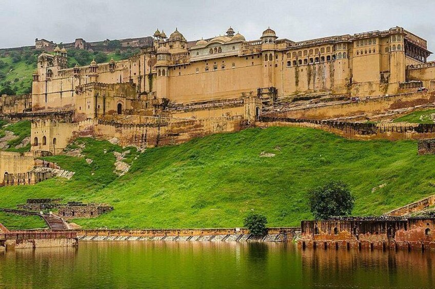 A large historical fort with a surrounding moat and lush green hills. 2