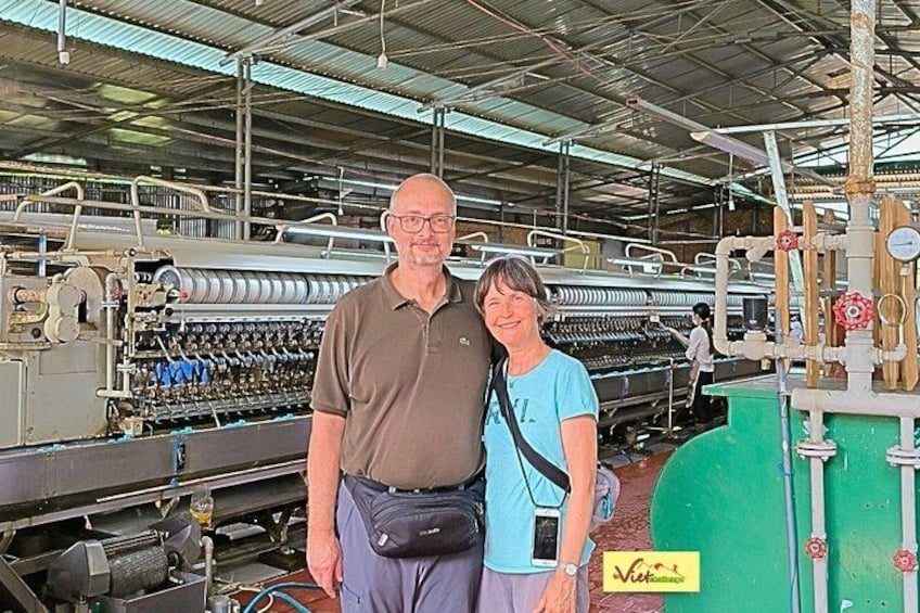 Two people standing in front of industrial machinery in a factory setting. 4