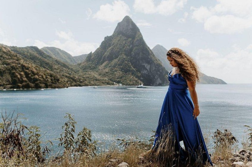 A person in a blue dress standing by a lake with mountains in the background. 3