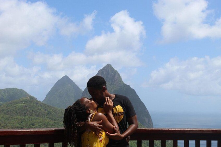 A couple embracing on a balcony with a mountainous landscape in the background. 1