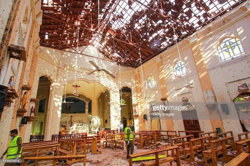 Interior de iglesia en ruinas, con vigas de madera expuestas, vidrieras y escombros dispersos. 2