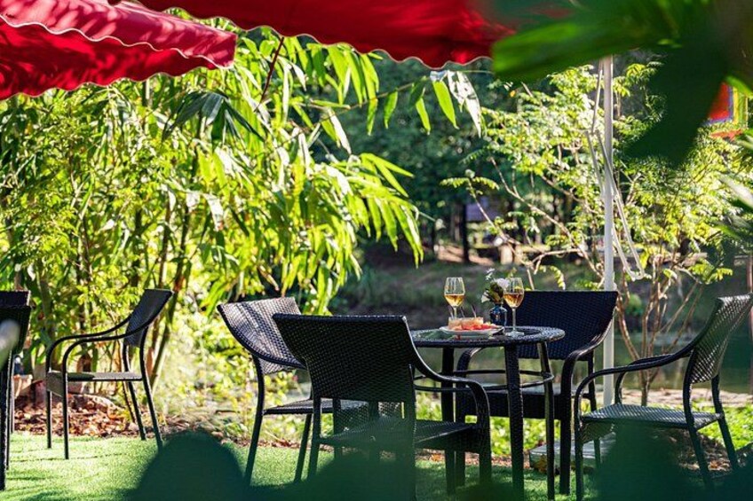 An outdoor dining area with tables and chairs, surrounded by lush greenery. 4