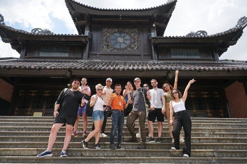 A group of people posing in front of a traditional building with a clock and ornate architecture. 1