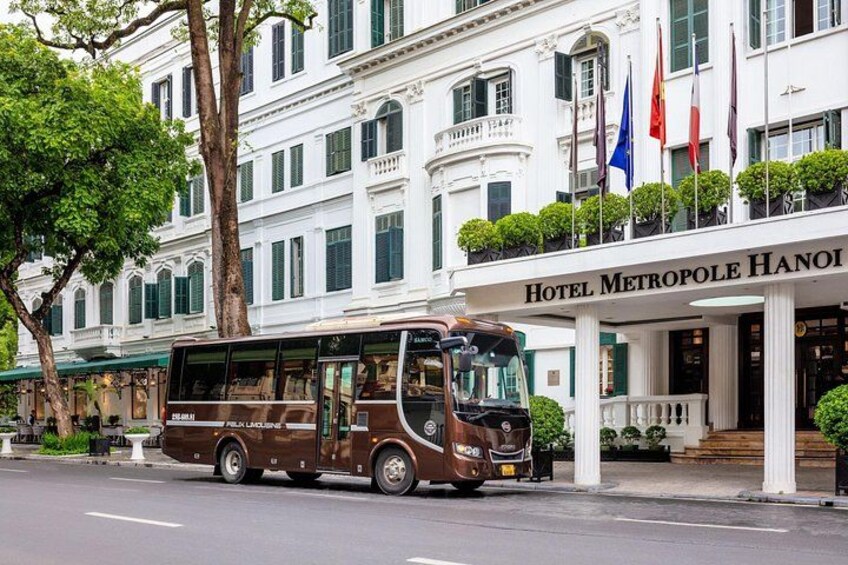 A brown bus parked in front of Hotel Metropole Hanoi. 3