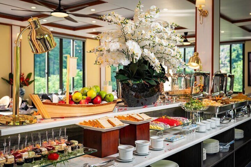A buffet with various food items, a potted orchid, and a decorative lamp. 3