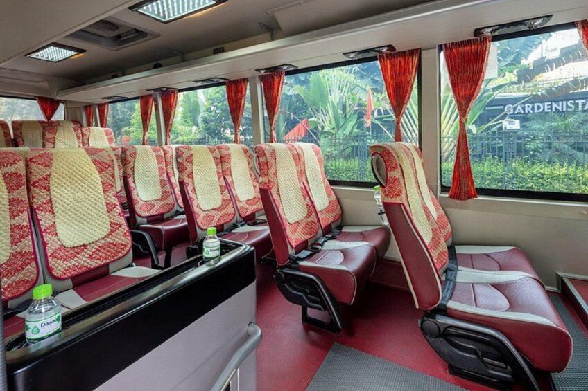 A train carriage with red and beige seats, a table with a bottle, and windows with red curtains. 2