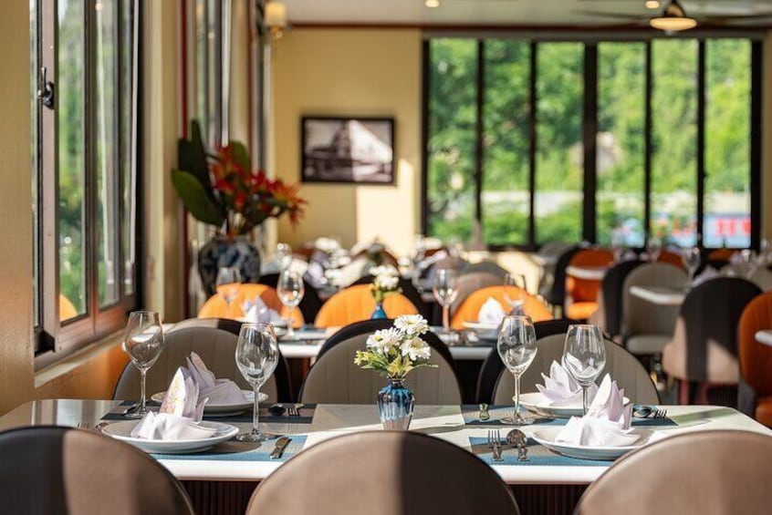 A restaurant with tables set for dining, chairs, and a vase with flowers. 4