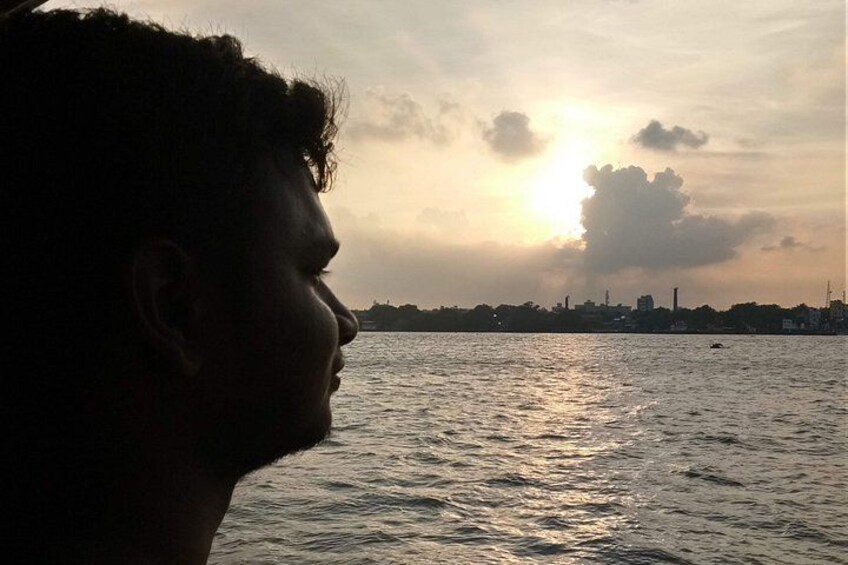 Silouette di una persona che guarda un tramonto su un corso d'acqua, con sullo sfondo la skyline di una città. 5