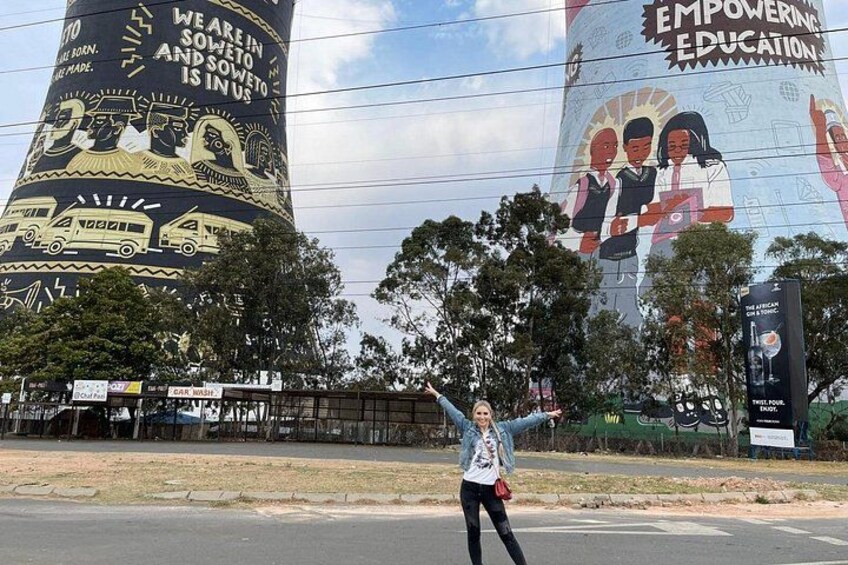 A person standing in front of a large mural with educational themes. 5