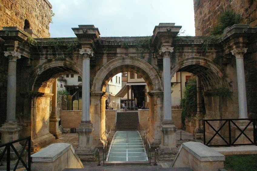 Un’antica arcata in pietra con colonne, che conduce a una scala e un edificio sullo sfondo. 1