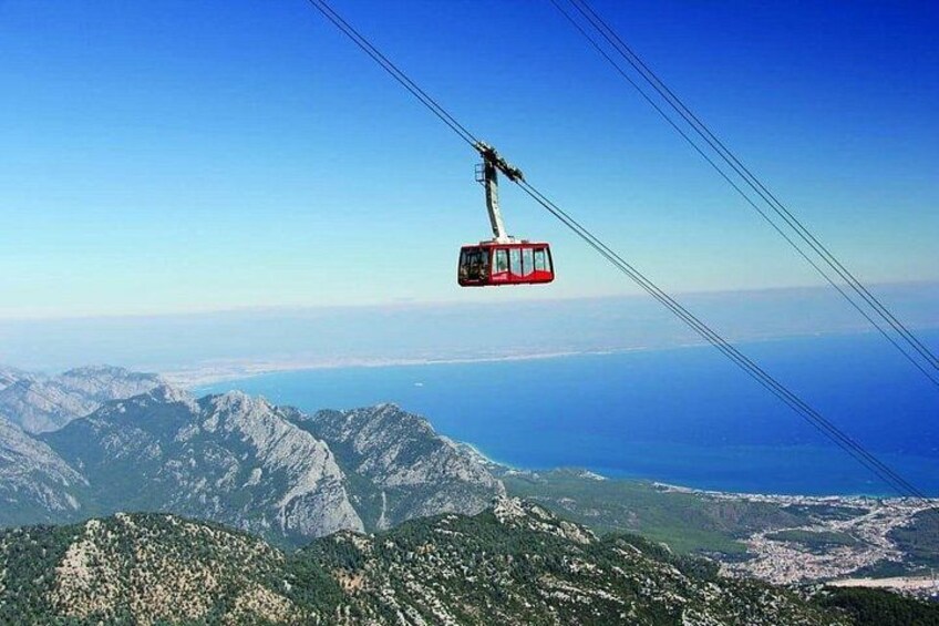 Een kabelbaan hangt boven een bergachtig landschap, met uitzicht op de oceaan eronder. 5