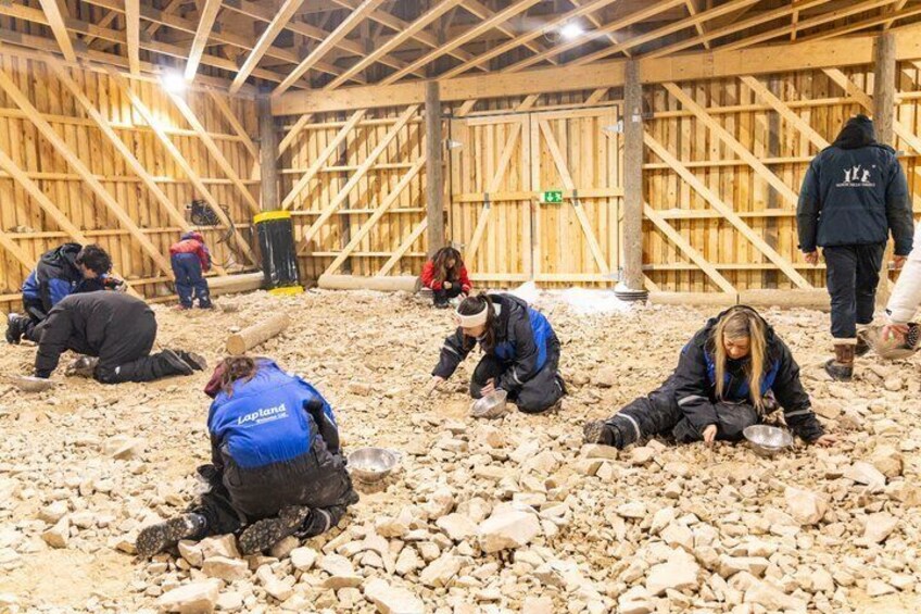 People working indoors, surrounded by wooden structures and gravel. 4